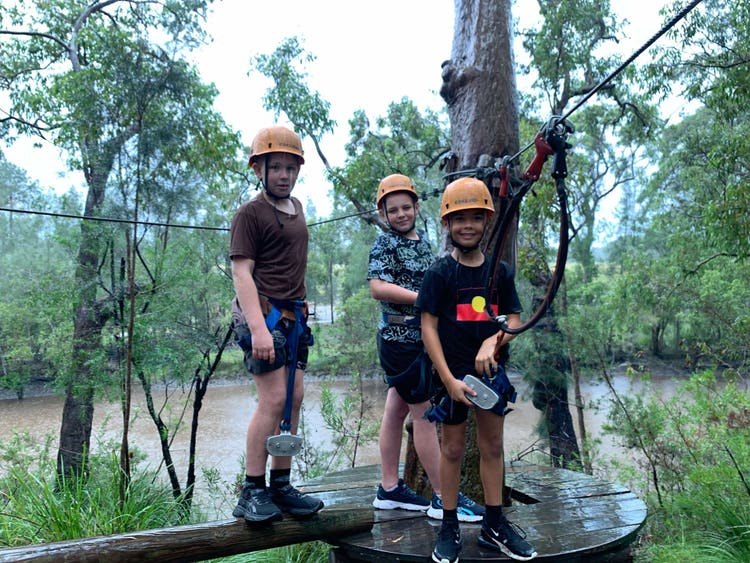 three students doing high ropes.