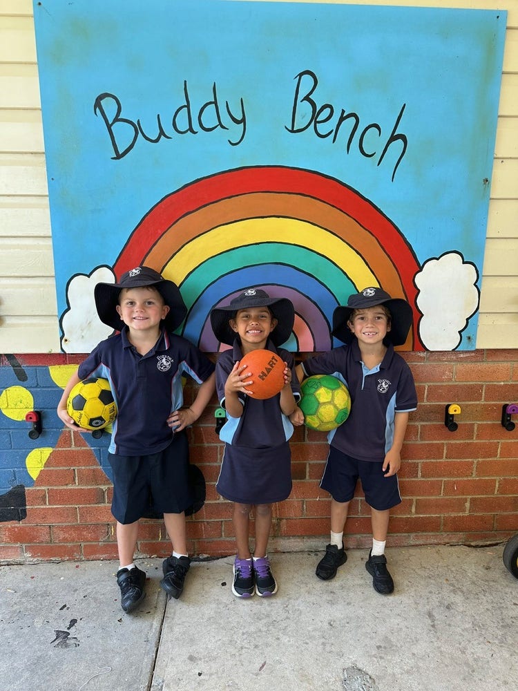 three students holding soccer balls in front of mural