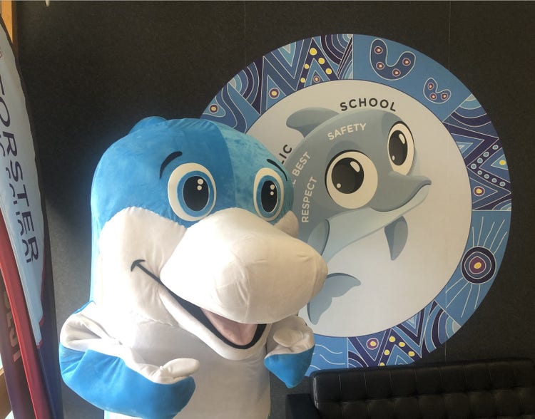dolphin mascot in front of dolphin mural