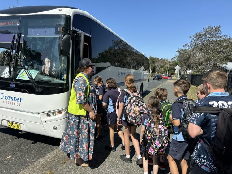 children alighting bus with teacher direction