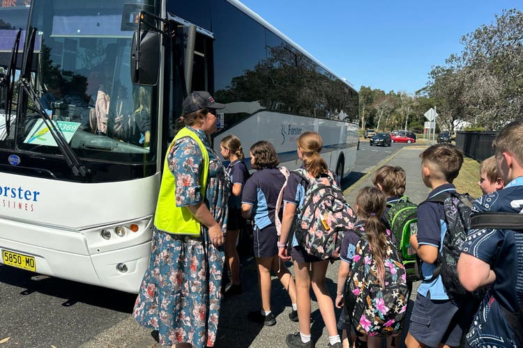 children alighting bus with teacher direction